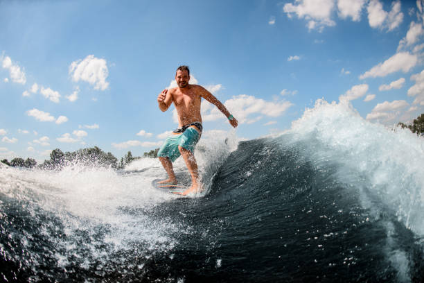 istock athletic guy actively ride on the waves on surfboard against blue sky 1256855710