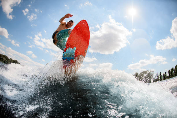 istock active man jumping on bright wakeboard down the river against the background of sky 1256855744