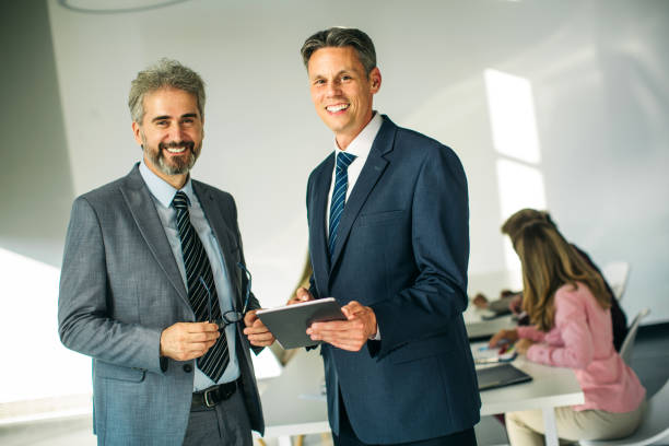 istock Two senior businessman talking and looking at tablet 1256856581