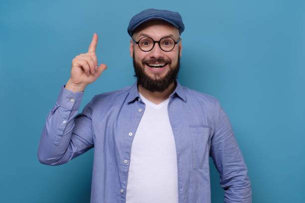 istock Man with beard in summer blue cap pointing at something 1256857229