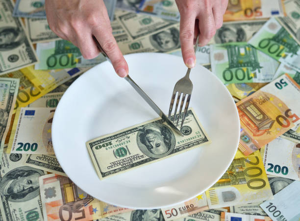 istock Dollar bills lie on a plate. Hand with a fork reaches for dollars. concept on the topic of finance 1256859933