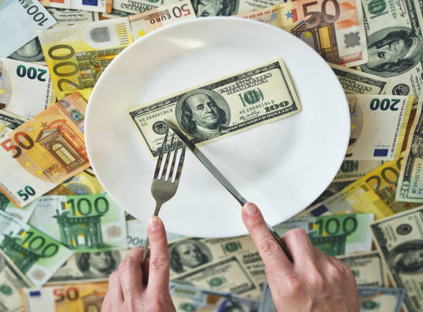 istock Dollar bills lie on a plate. Hand with a fork reaches for dollars. concept on the topic of finance 1256860053
