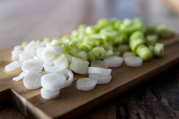 Chopped spring onions on wooden cutting board stock photo