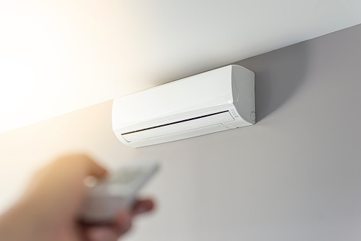 A man shutting down the air conditioner with remote control. Selective focus on the air conditioner.