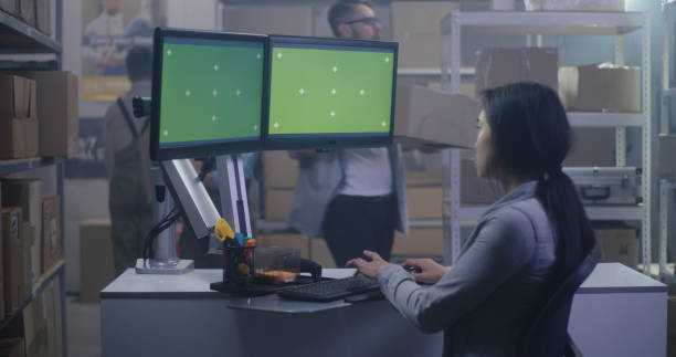 istock Young woman working at a computer in a distribution center 1256863953