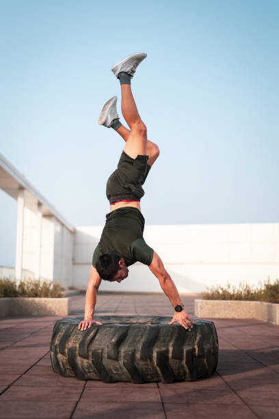 istock Man practicing hand stand on a tractor tire outdoors 1256864569