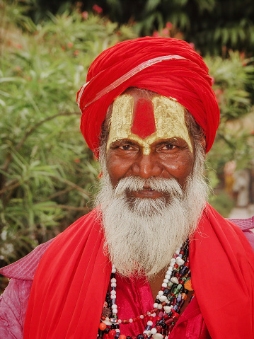 Rajasthan India - 23 November, 2004: Indian sadhu in red clothing , painted face and personal accessories, is smiling and  looking at the camera.