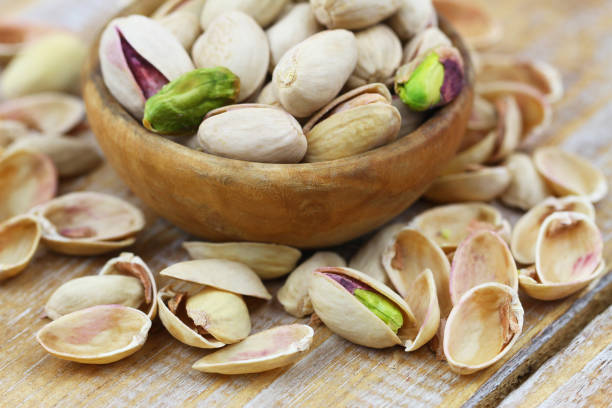 istock Pistachio nut among open pistachio nutshells on wooden surface 1256869257