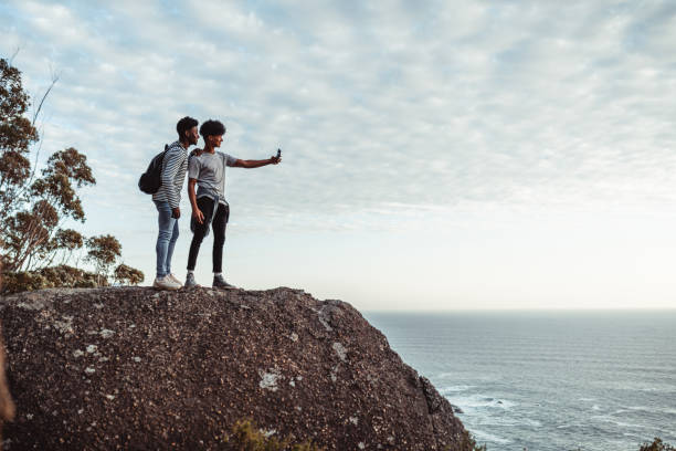 Two young men taking selfie on the edge of the cliff Two young men taking selfie on the edge of the cliff cape town photos stock pictures, royalty-free photos & images