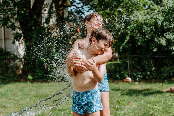 istock Brothers playing with water in the yard 1256870971