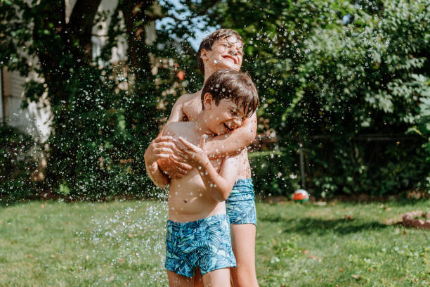 istock Brothers playing with water in the yard 1256871006