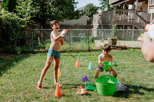 Brothers playing with water in the yard on a hot sunny day