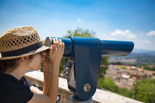 Little girl child looking through binoculars outdoors on sunny summer day
