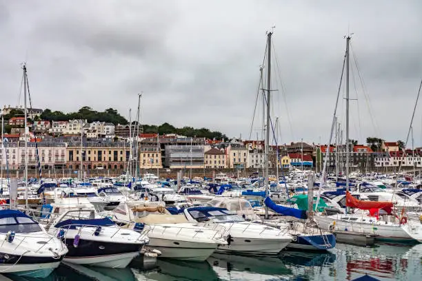 Photo of Town of Saint Peter Port under a moody sky overlooking a fully occupied Marina on the Isle of Guersney