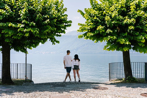 Young couple of tourists embraced in front of the lake, Como Lake, Bellagio, Italy.