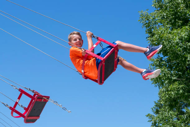 istock Tween Boy Enjoying Chain Swing Amusement Ride in a Public Park on a Summer Afternoon 1256880033