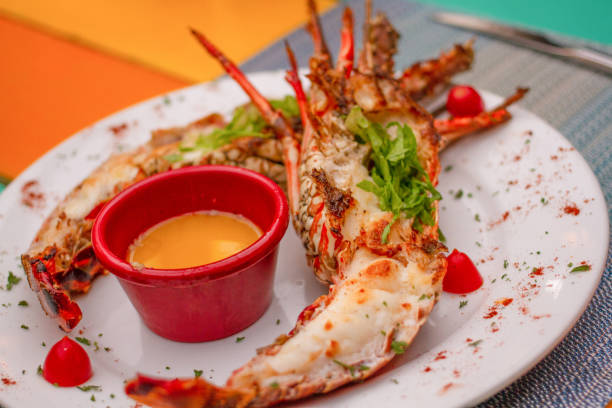istock Dish with a cut and cooked lobster decorated with lettuce and accompanied by a sauce on a colorful wooden table 1256880141