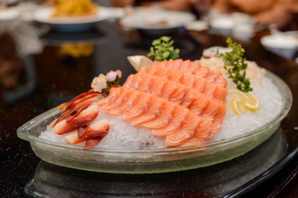 istock Fresh salmon sashimi, lemon slices and greenery on ice 1256885948