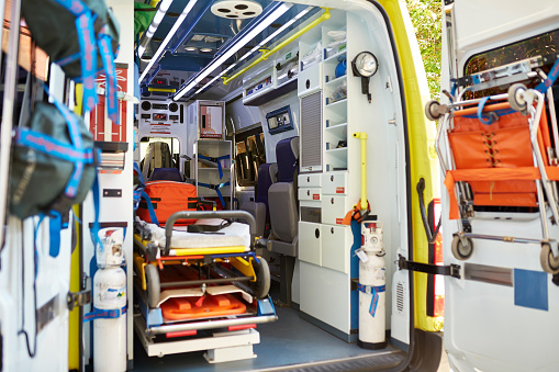 View from open rear doors of unoccupied ambulance interior with equipment required to stabilize an ill or injured person and transport them to hospital.