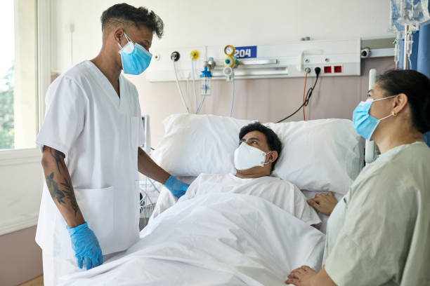 enfermera joven masculina al lado de la cama del paciente covid-19 recuperable - filipino ethnicity asian ethnicity men male fotografías e imágenes de stock