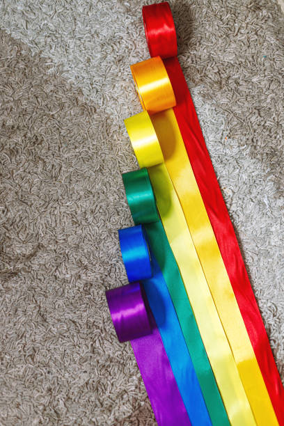 ribbons in the color of the lgbt rainbow flag in bobbins are rolled out on the carpet using how to celebrate homosexuals, gay, lesbian and concepts ribbons in the color of the lgbt rainbow flag in bobbins are rolled out on the carpet using how to celebrate homosexuals, gay, lesbian and concepts rainbow flag photos stock pictures, royalty-free photos & images