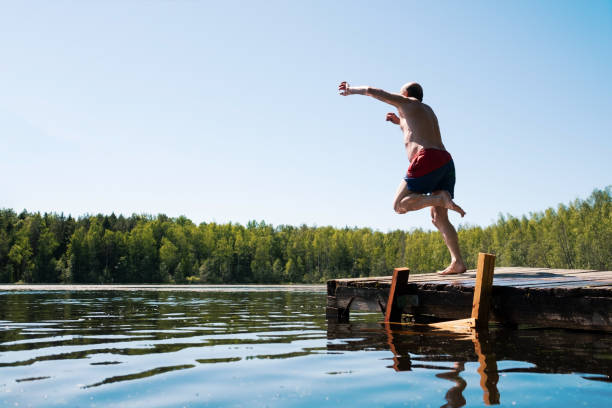 istock Man jump to lake water having fun during vacation. 1256895886