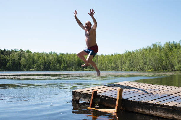 istock Man jump to lake water having fun during vacation. 1256895919
