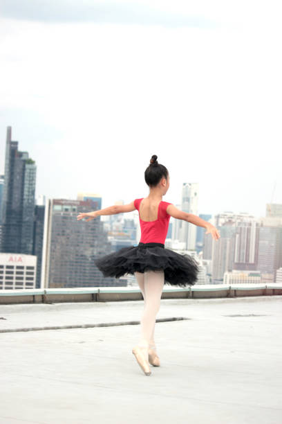istock Asian ballerina dancer girl practicing ballet dancing on rooftop with skyscraper city view, adorable child dancing in ballet 1256896785