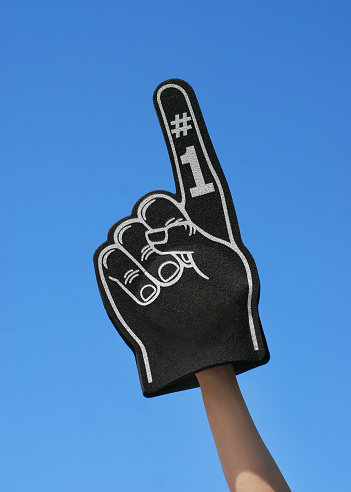 Closeup of a fan wearing a foam finger at a sporting event.