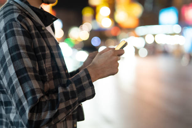 istock Young man holding cell phone waiting for car 1256899355