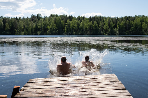 Man and woman jumping into lake water at summer vacation