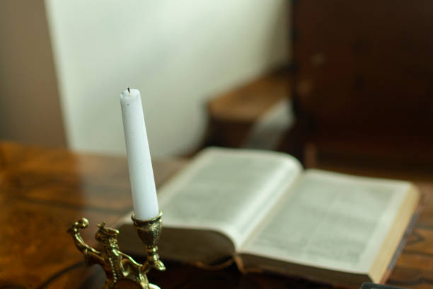 istock a candle in a candlestick next to a book on the table 1256899707