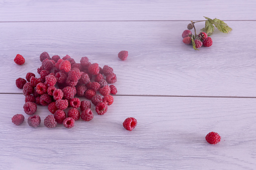 a pile of ripe fresh raspberries on a wooden background