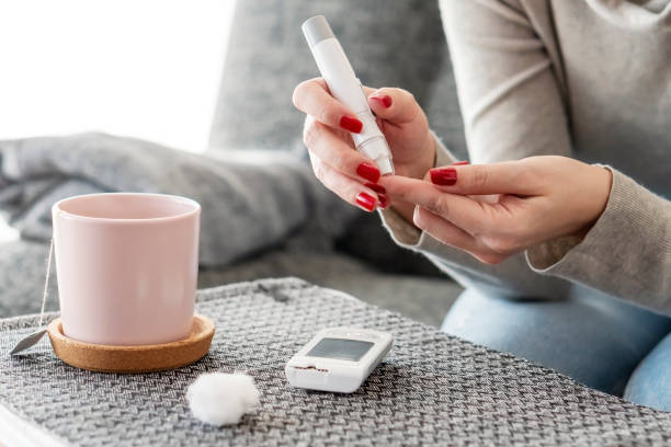 mid adult diabetic woman checking glucose level at home - bg imagens e fotografias de stock