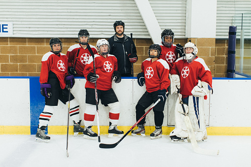 Portrait of a women's hockey team dressed up in their recreation league uniforms with their coach. They are posing on the ice before their game. Image taken in Utah, USA.