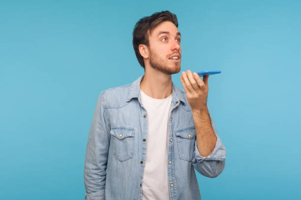 inteligentna technologia głosowa. portret pozytywnego przystojnego mężczyzny w dżinsowej koszuli rozmawiającej z telefonem komórkowym - to do list audio zdjęcia i obrazy z banku zdjęć