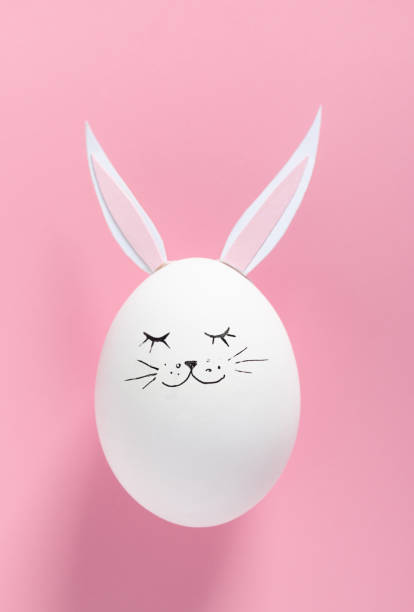 istock Easter egg with bunny ears and face on pink background with copy space. Flat lay. Minimal concept. Conceptual creative photo approaching Happy Easter holiday. 1256904943