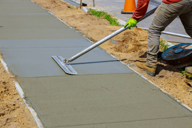 istock Mason building a screed coat cement a laborer floats a new concrete sidewalk 1256905906
