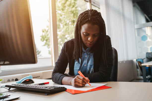 jovem empresária fazendo anotações em sua mesa em um escritório moderno - to do list checklist personal organizer writing - fotografias e filmes do acervo