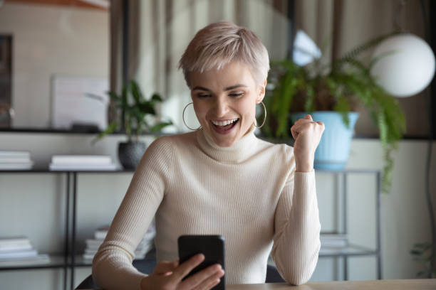 スマートフォンを持っている従業員は、電子銀行アプリの小切手残高を使用して幸せを感じます - perks ストックフォトと画像