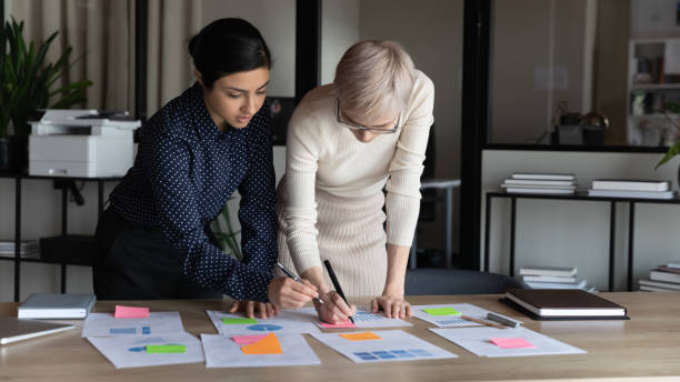 multi racial businesswomen working on project statistics in office - note pad desk office meeting imagens e fotografias de stock