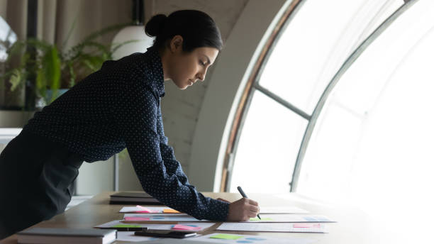 Indian businesswoman do financial stats analysis writing data makes overview