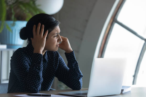 istock Overworked Indian employee sitting at workplace suffering from headache 1256907188