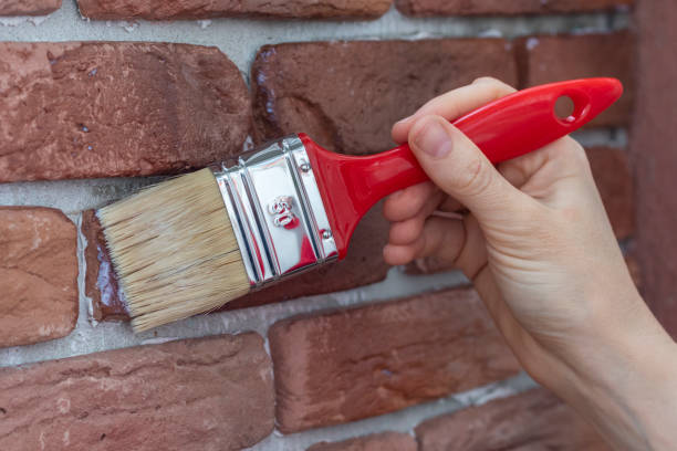 istock Female hand applying varnish to decorative plaster tile. 1256908362