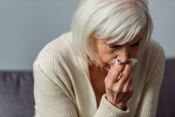 istock depressed senior woman crying while holding paper napkin 1256908732