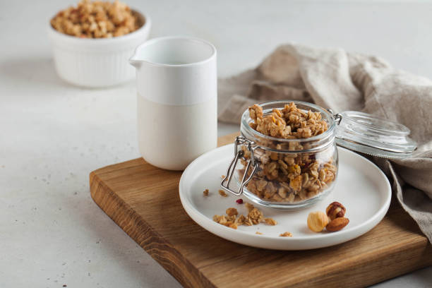 domowej roboty granola z orzechami w szklanym słoiku na drewnianej desce. zdrowa koncepcja śniadania, śniadanie wegetariańskie. kopiuj miejsce - jar oatmeal granola glass zdjęcia i obrazy z banku zdjęć