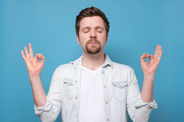 istock Handsome guy meditating with raised hands and zen gesture, being relaxed 1256912225