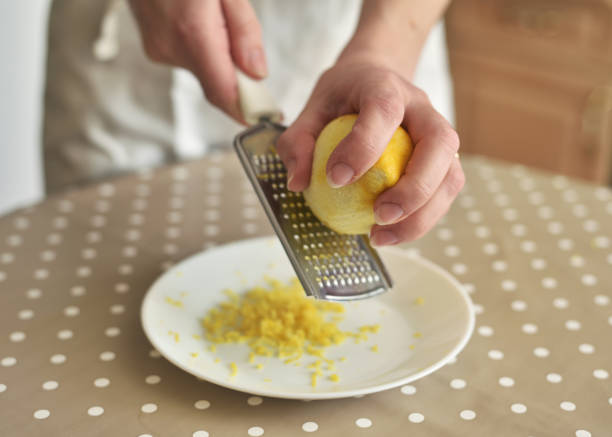 primo piano della donna che strofina la scorza di limone sulla grattugia - grater foto e immagini stock