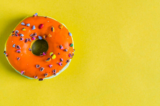 istock An orange color donut on a yellow background 1256914072