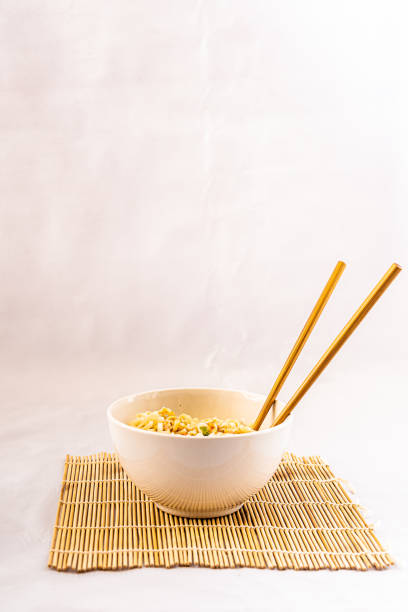 A white bowl of noodles on a wire background